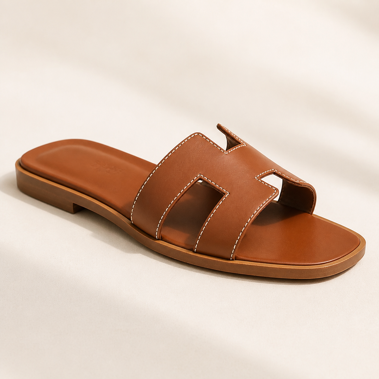 Sandalias planas de piel para mujer en color neutro sobre fondo claro, vista frontal mostrando el diseño deslizante minimalista